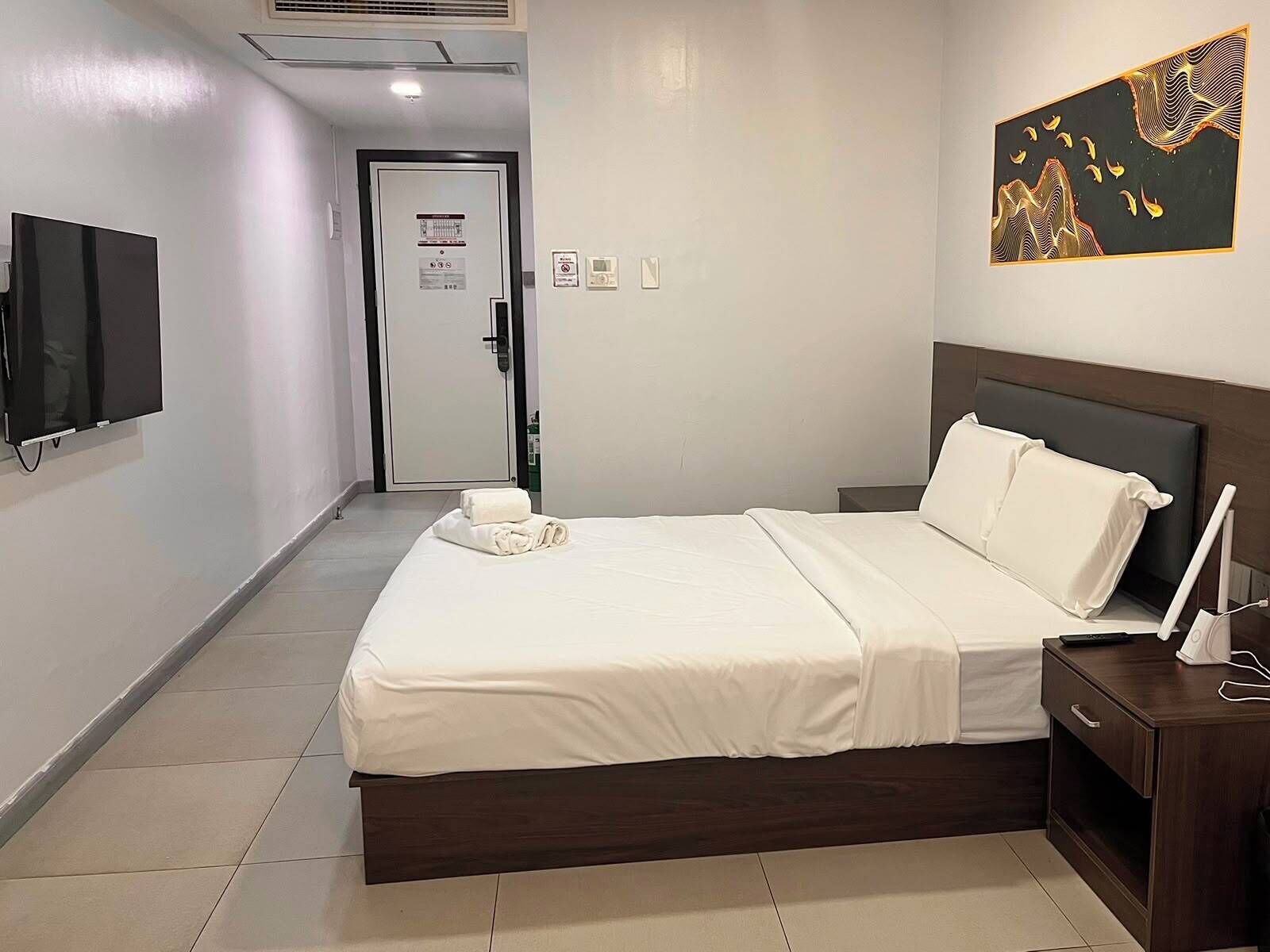Habitación de hotel con cama, mesita de noche y televisión de pantalla plana.