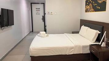 Ein Hotelzimmer mit Bett, Nachttisch und Flachbildfernseher.