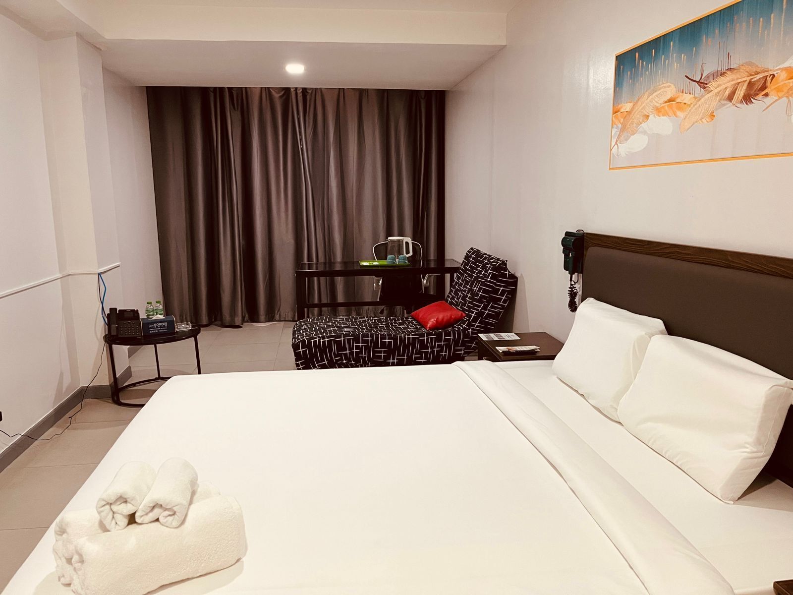 Habitación de hotel con una cama grande, un escritorio, una silla y un cuadro en la pared.