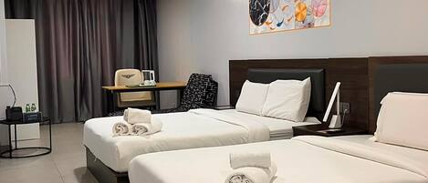A hotel room with two beds, a desk, and a wall-mounted artwork.