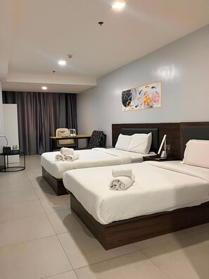 A hotel room with two beds, a desk, and a wall-mounted artwork. - LUNA HOTEL (Pasay)