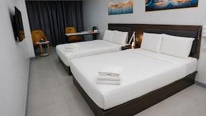 A hotel room with two beds, a desk, a chair, and artwork on the walls.