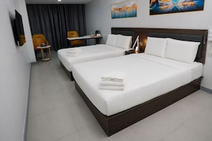 Habitación de hotel con dos camas, un escritorio, una silla y obras de arte en las paredes.