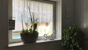 Una ventana con una planta en maceta, un cartel con texto y una placa en la pared.