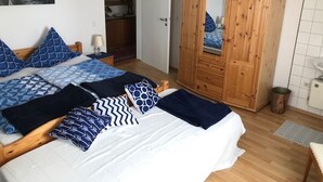 Un dormitorio con cama, un armario de madera, un espejo y vistas al mar.