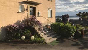 Un bâtiment à deux étages, à la façade de couleur beige, doté d’une entrée principale et d’un petit porche avec des marches menant à l’entrée.