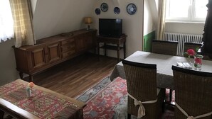 Un espace repas comprenant une table, des chaises, un téléviseur et un meuble.