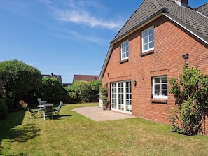 A brick house with a well-maintained lawn, a patio, and a garden area. - Amselhaus - Beautiful detached house with 120 m², 5 rooms and a large garden for up to (Sylt)