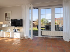 A spacious living room with a television, books, and a radiator. - Amselhaus - Beautiful 120 m² single-family home with 5 rooms and a large yard, suitable for up to (Sylt)