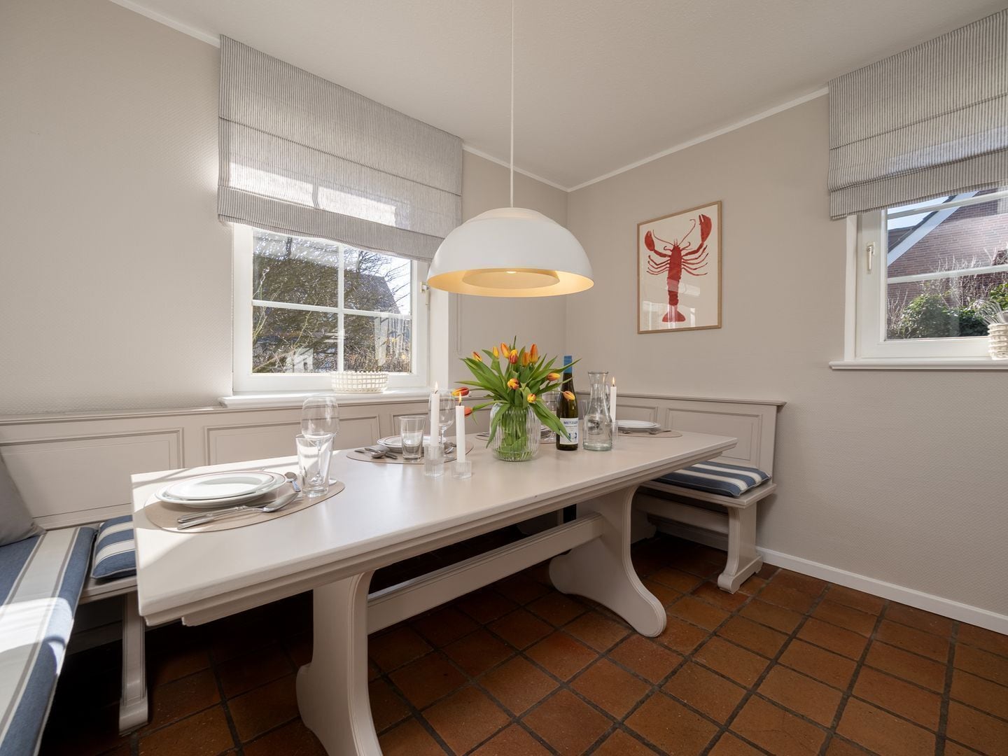 Comedor con una mesa blanca para cuatro, un banco y un ventanal con cortinas.