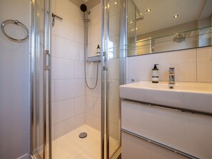 A modern bathroom with a glass-enclosed shower, a white sink with a mirror, and a bottle of shampoo on the counter. - Amselhaus - Beautiful detached house with 120 m², 5 rooms and a large garden for up to (Sylt)