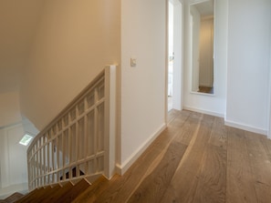 A staircase with wooden steps and white railings, leading to a room with a large mirror and a door. - Amselhaus - Beautiful detached house with 120 m², 5 rooms and a large garden for up to (Sylt)