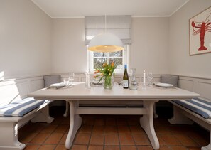A dining table with benches, a vase of flowers, wine glasses, and a candle. - Amselhaus - Beautiful detached house with 120 m², 5 rooms and a large garden for up to (Sylt)