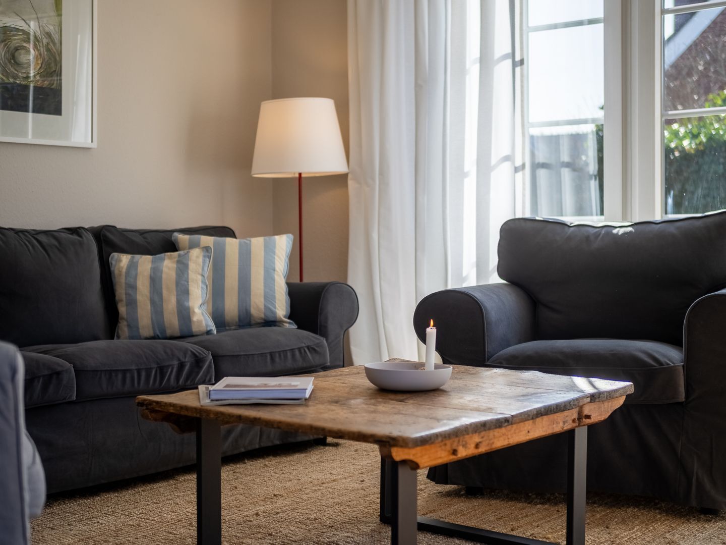 A modern living room with a dark grey sofa, a wooden coffee table, and a floor lamp.
