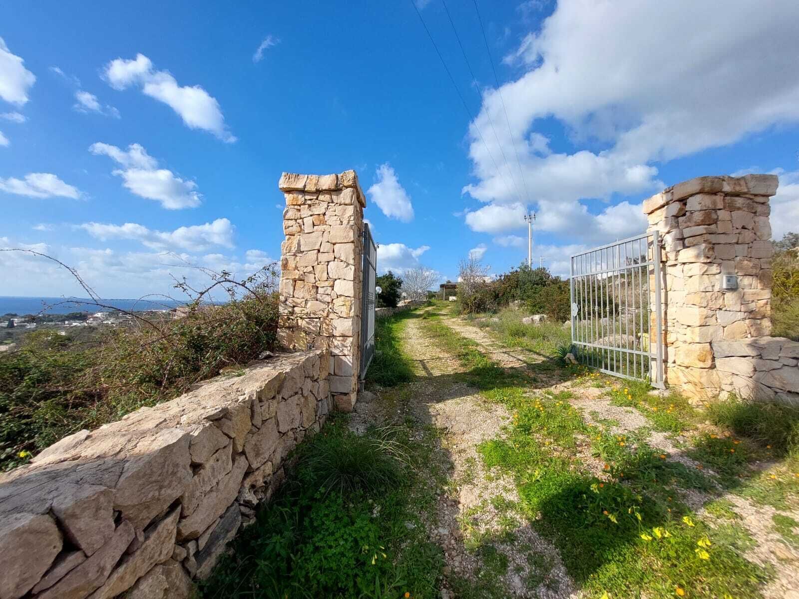 Uma trilha de pedra leva a um portão com vista ampla da paisagem ao redor.