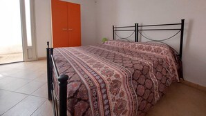 Un dormitorio con una cama, un armario naranja y una ventana.