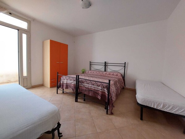 Un dormitorio con cama, armario y ventana.
