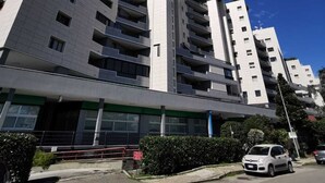 Un immeuble moderne à plusieurs étages, doté d’un toit plat et d’une combinaison de balcons et de fenêtres.