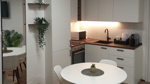 Une cuisine moderne avec des meubles blancs, une table de salle à manger ronde et un four encastré.