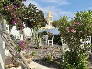 Ein Innenhof mit weißer Möbel, Kakteen und Bougainvillea.