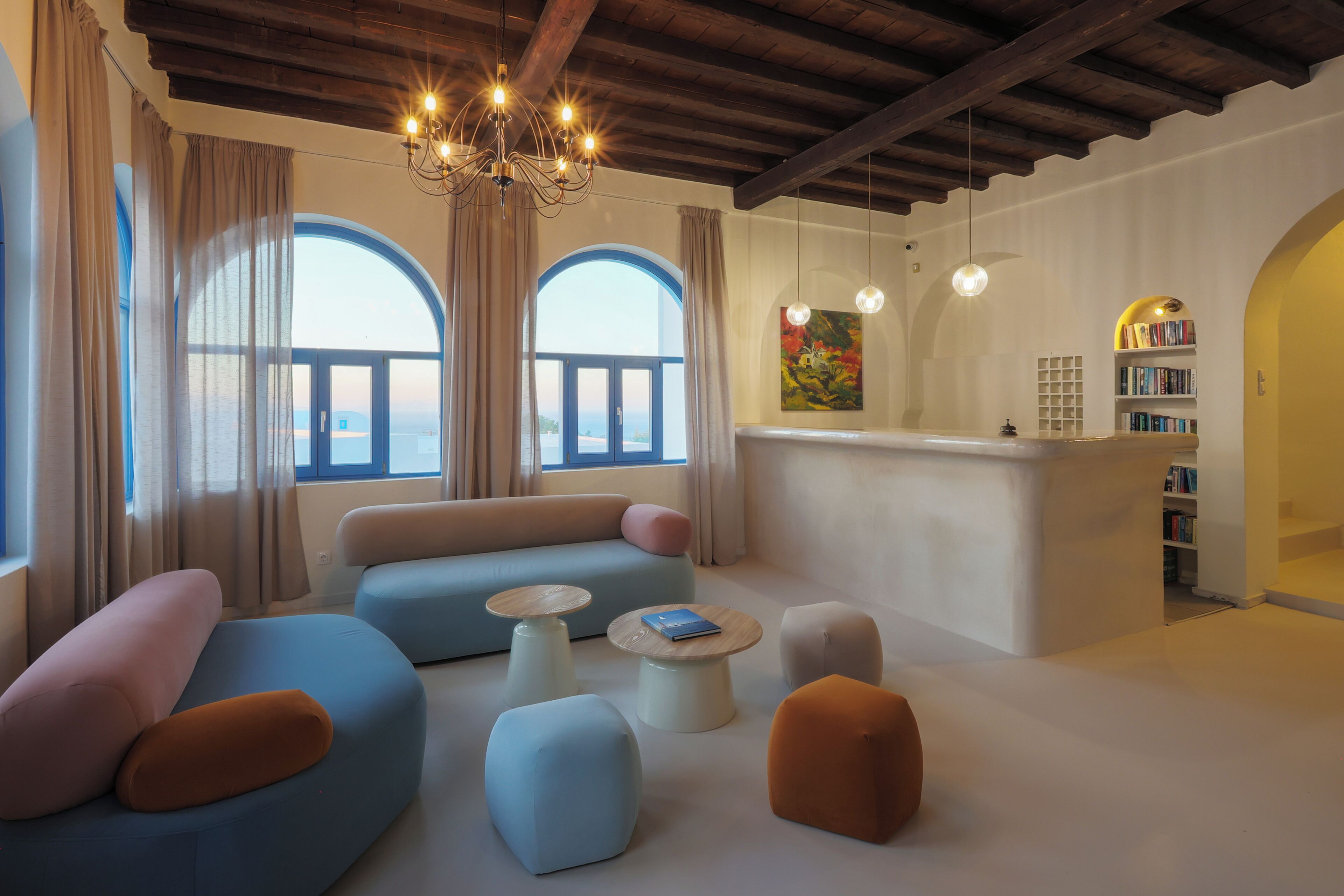 A modern living room with a sofa, ottomans, a coffee table, a bookshelf, and a painting.