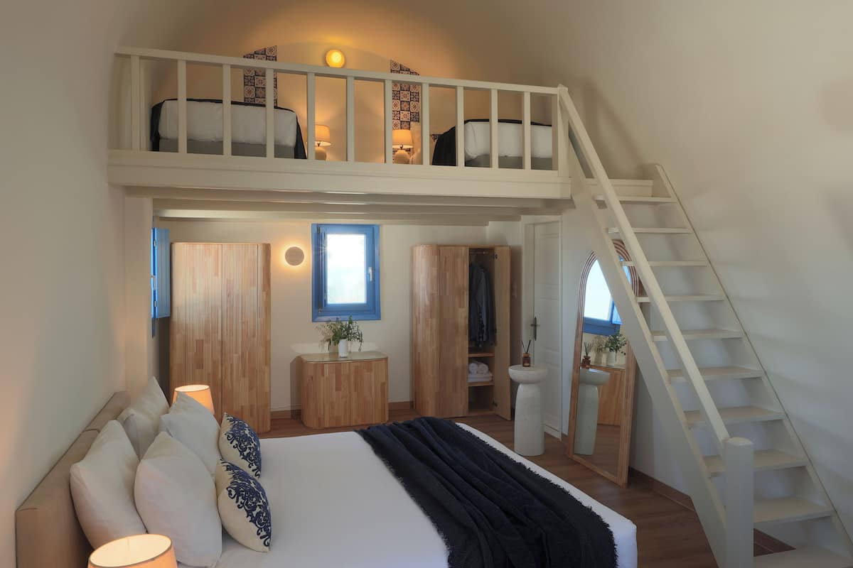 Een slaapkamer met een stapelbed, nachtkastjes, een spiegel en een trap.