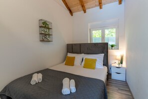 A bedroom with a bed, two bedside tables, a window, and a wall-mounted shelf with plants. - Villa Mia near Zadar (Glavica)