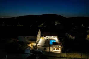 Ein Haus mit Swimmingpool, überdachter Terrasse und Garage.