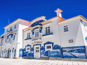 Een wit gebouw met blauwe decoratieve details en een betegelde ingang.