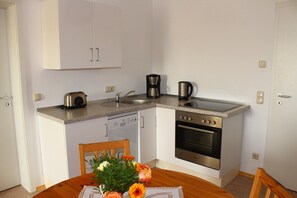 A compact kitchen with a dishwasher, stove, coffee maker, and a sink. - XXL Ferienhaus in Struppen (Struppen)