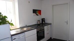 Eine Küche mit Geschirrspüler, Backofen, Kaffeemaschine und Spüle.