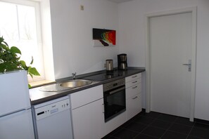 A kitchen with a dishwasher, oven, coffee maker, and a sink. - XXL Ferienhaus in Struppen (Struppen)