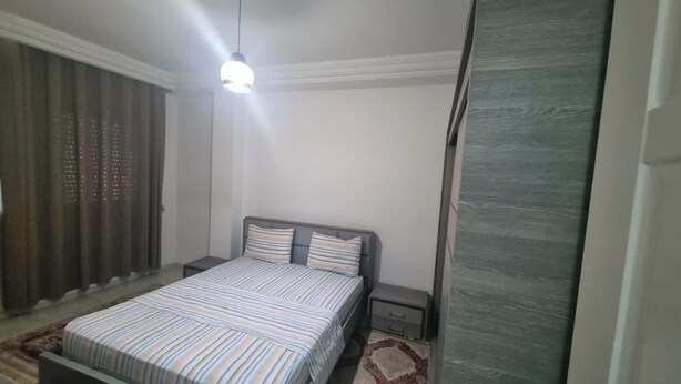 A bedroom with a bed, a nightstand, a lamp, and a window with curtains. - Your haven of comfort in Sfax Bienvenue Chez Moi (Sfax)