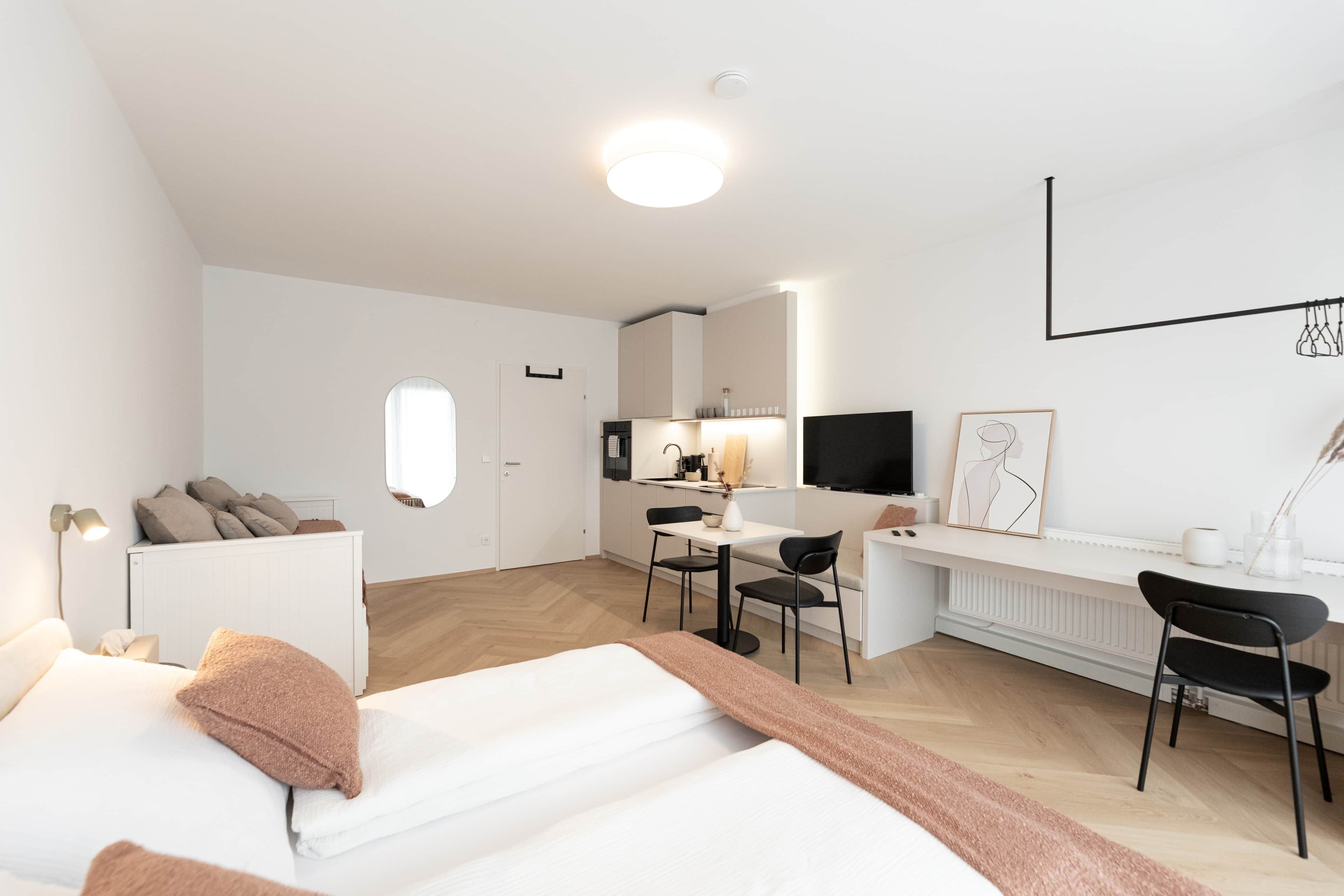 Una habitación de hotel moderna con una cama, un escritorio y un kitchenette.