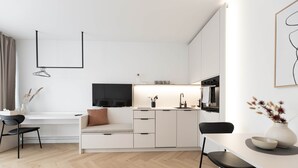 Eine moderne Küche mit weißen Schränken, einem Essbereich mit Tisch und Stühlen sowie einem integrierten Fernseher.