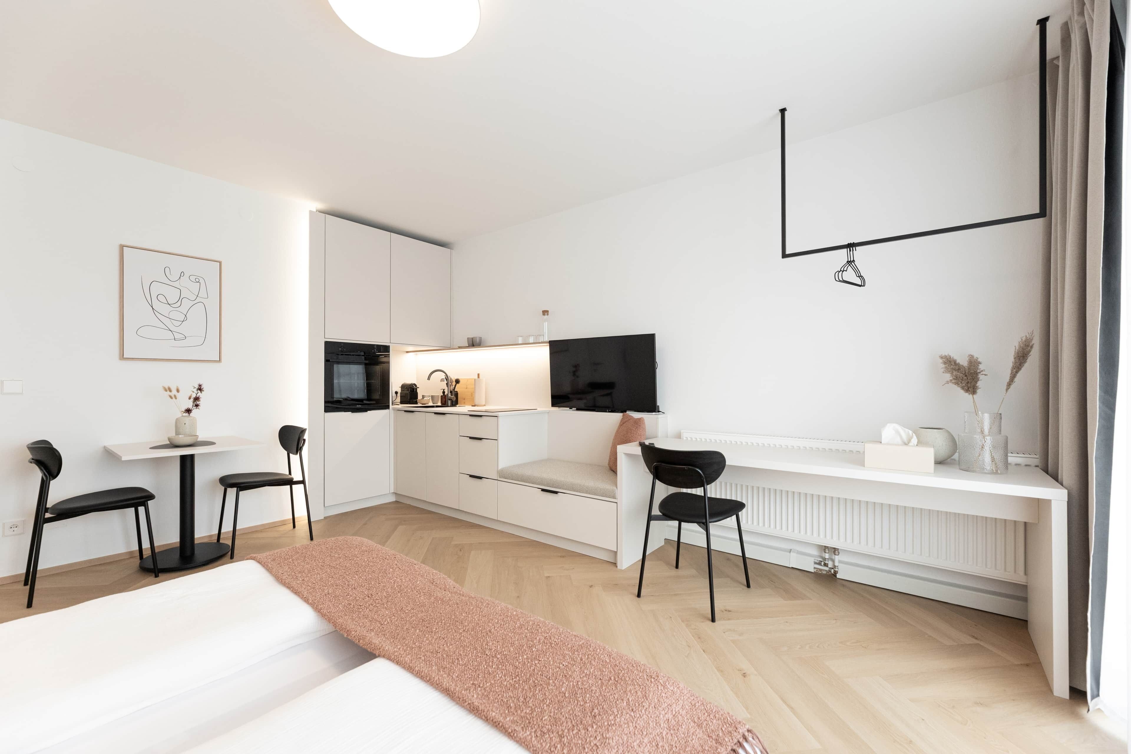 Een moderne, minimalistische hotelkamer met een bed, een bureau, een stoel, een televisie en een radiator.