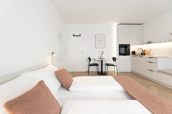 Une chambre d’hôtel moderne équipée d’un lit, d’une petite table à manger et d’une kitchenette.