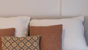 A sofa with three pillows in different patterns and colors.