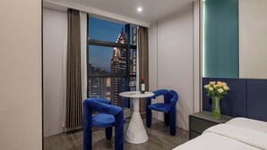 A hotel room with a city view, a round table with chairs, a bed, and a nightstand with a vase of flowers. - Chongqing Jiefangbei Centre Bairui Hotel (Chongqing)