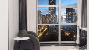 A modern living room with a large window offering a cityscape view at dusk. - Chongqing Jiefangbei Centre Bairui Hotel (Chongqing)