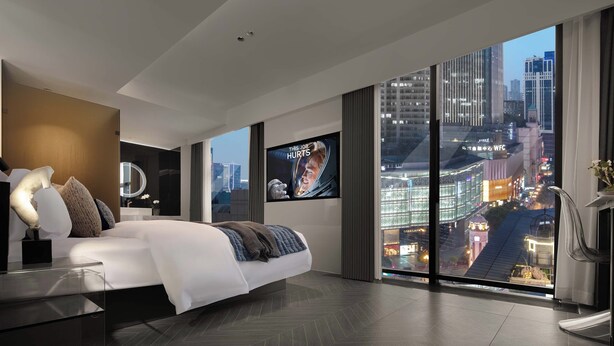 A modern hotel room with a large bed, a television, and a city view. - Chongqing Jiefangbei Centre Bairui Hotel (Chongqing)