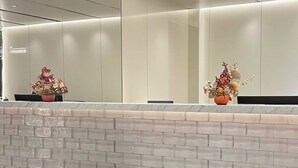 A modern restroom with a white brick wall, a bench, and a mirror with a vase of flowers. - Chongqing Jiefangbei Centre Bairui Hotel (Chongqing)