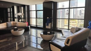 A modern living room with a large window, a black leather sofa, a white sofa, and a glass coffee table. - Chongqing Jiefangbei Centre Bairui Hotel (Chongqing)