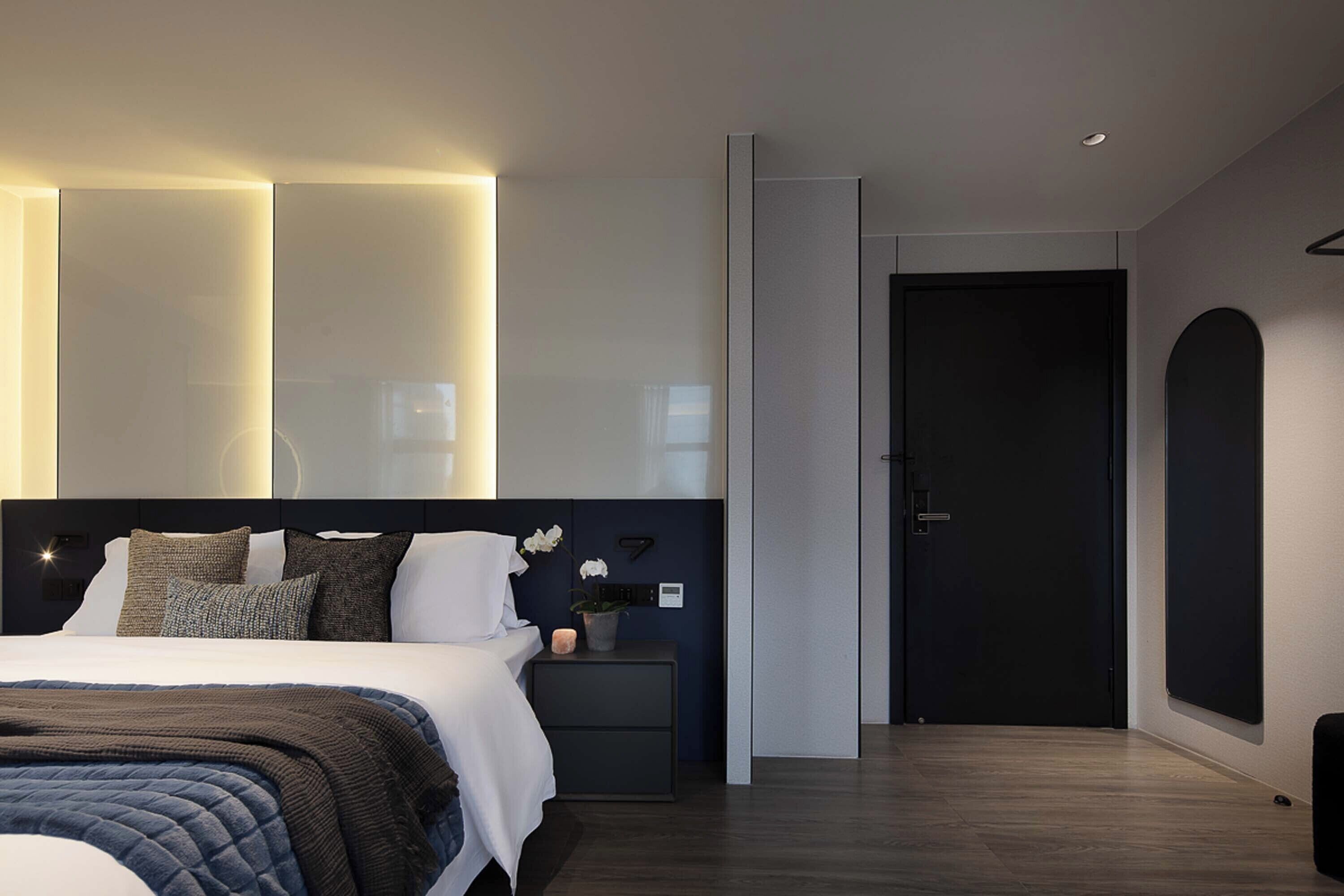 Une chambre à coucher moderne avec un grand lit, des tables de chevet, une commode et une porte.