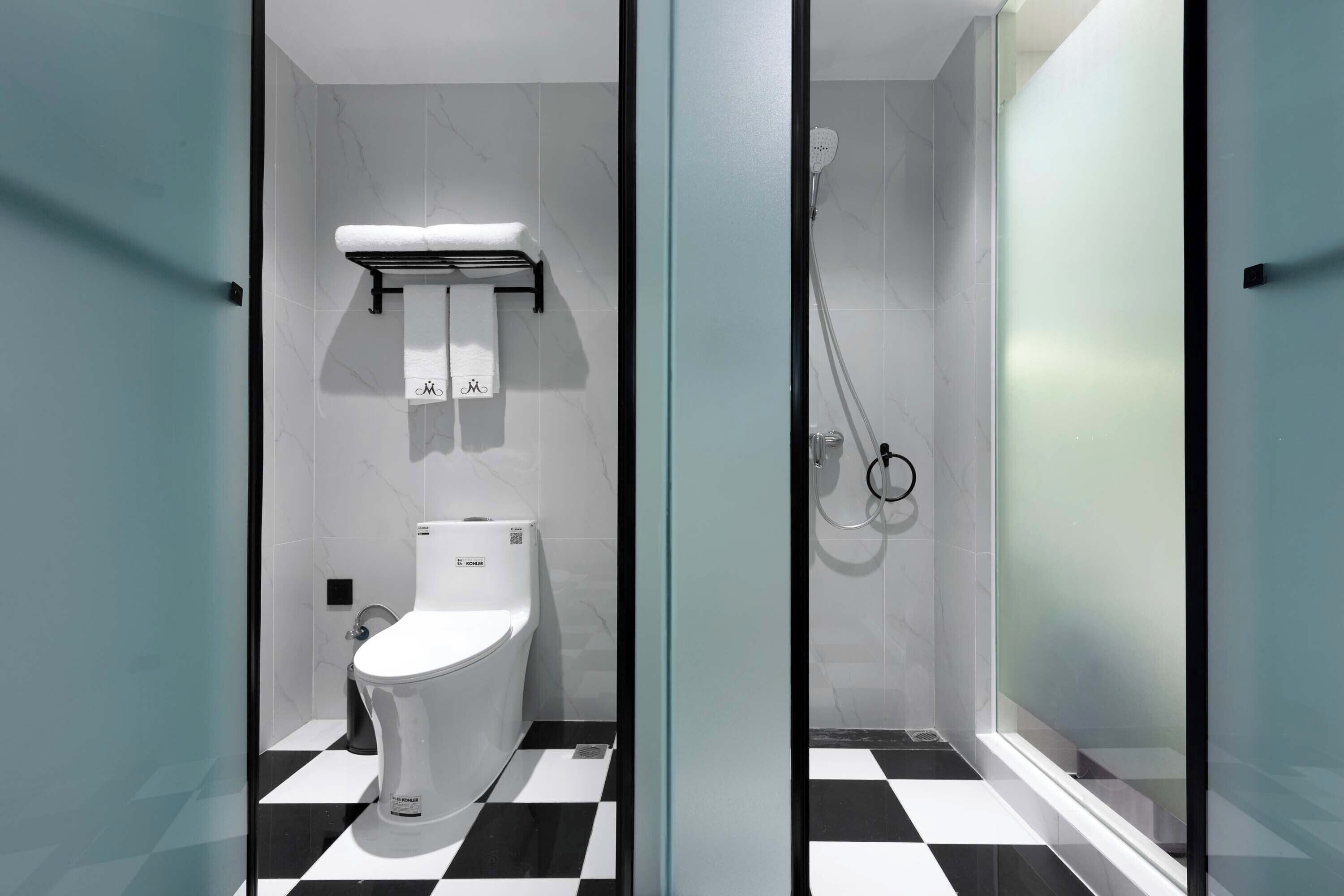 A modern bathroom with a toilet, a shower, and a checkered floor.