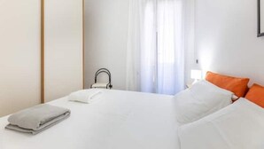 Une chambre d’hôtel avec un lit, des rideaux blancs, une fenêtre et une serviette sur le lit.