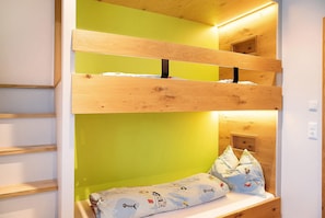 A bunk bed with a green wall and a wooden headboard. - Apartment "Wildschön" with Mountain Views, Shared Garden and Wi-Fi (Grafenweg)