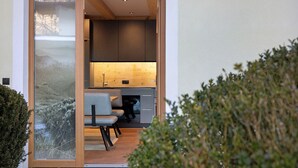 A modern kitchen with wooden cabinets, a built-in oven, and a dining area with a table and chairs. - Apartment "Wildschön" with Mountain Views, Shared Garden and Wi-Fi (Grafenweg)