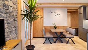 A modern kitchen with a stone wall, wooden ceiling, and a bench at the table. - Apartment "Wildschön" with Mountain Views, Shared Garden and Wi-Fi (Grafenweg)