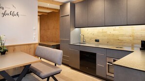 A modern kitchen with grey cabinets, a wooden ceiling, and a built-in sink. - Apartment "Wildschön" with Mountain Views, Shared Garden and Wi-Fi (Grafenweg)